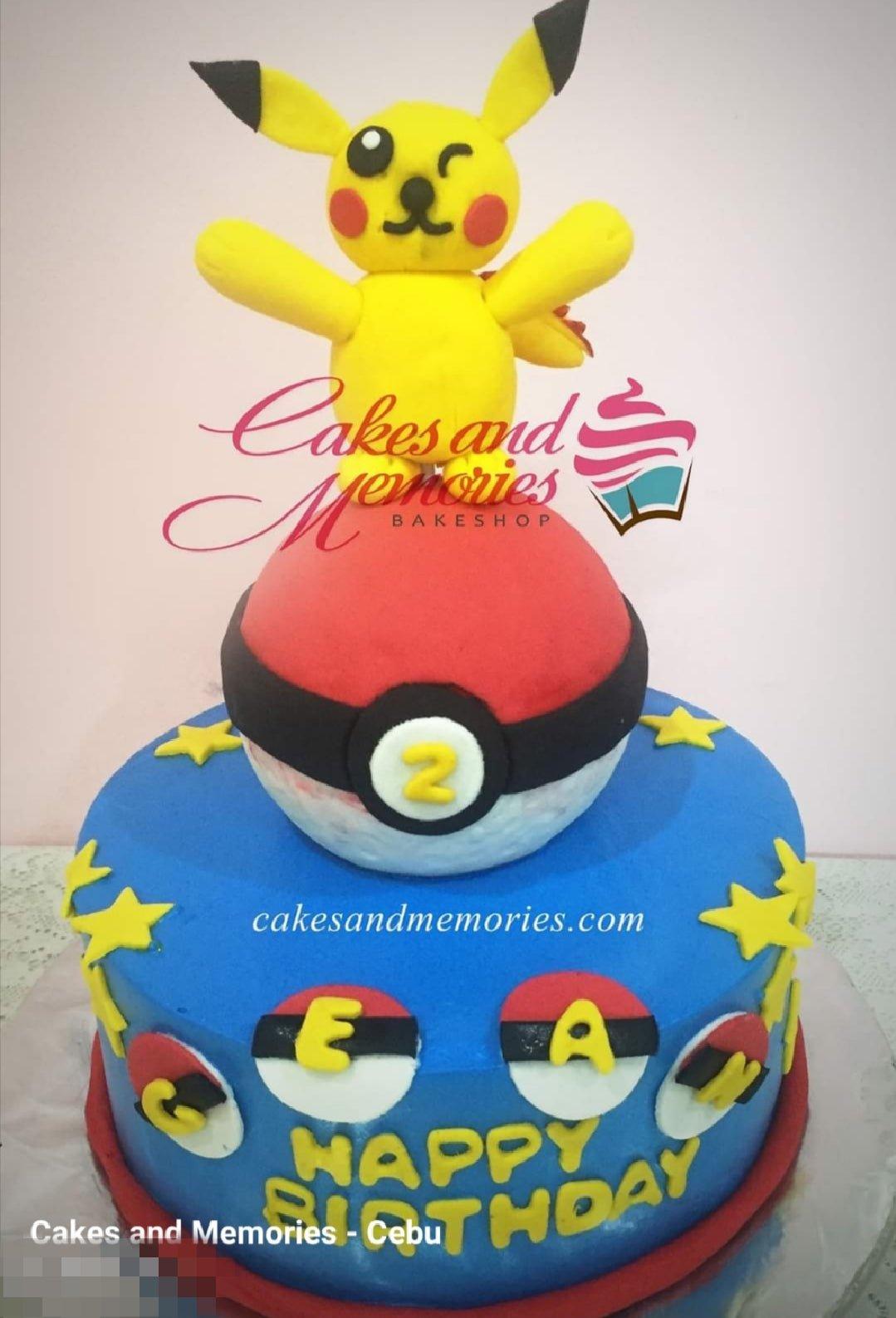 Blue Pokemon themed birthday cake with a large 3D Pikachu figure on a Pokeball and yellow stars.