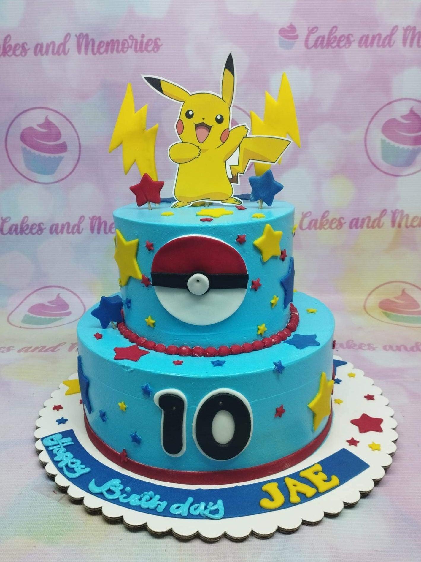 Two-tier light blue Pokemon themed cake featuring a Pikachu printout topper, lightning bolts, and a Pokeball decoration.