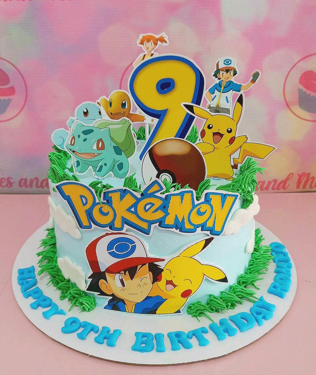 Light blue Pokemon birthday cake with Ash, Pikachu, Bulbasaur, Squirtle, and Charmander printout toppers and green icing grass borders.