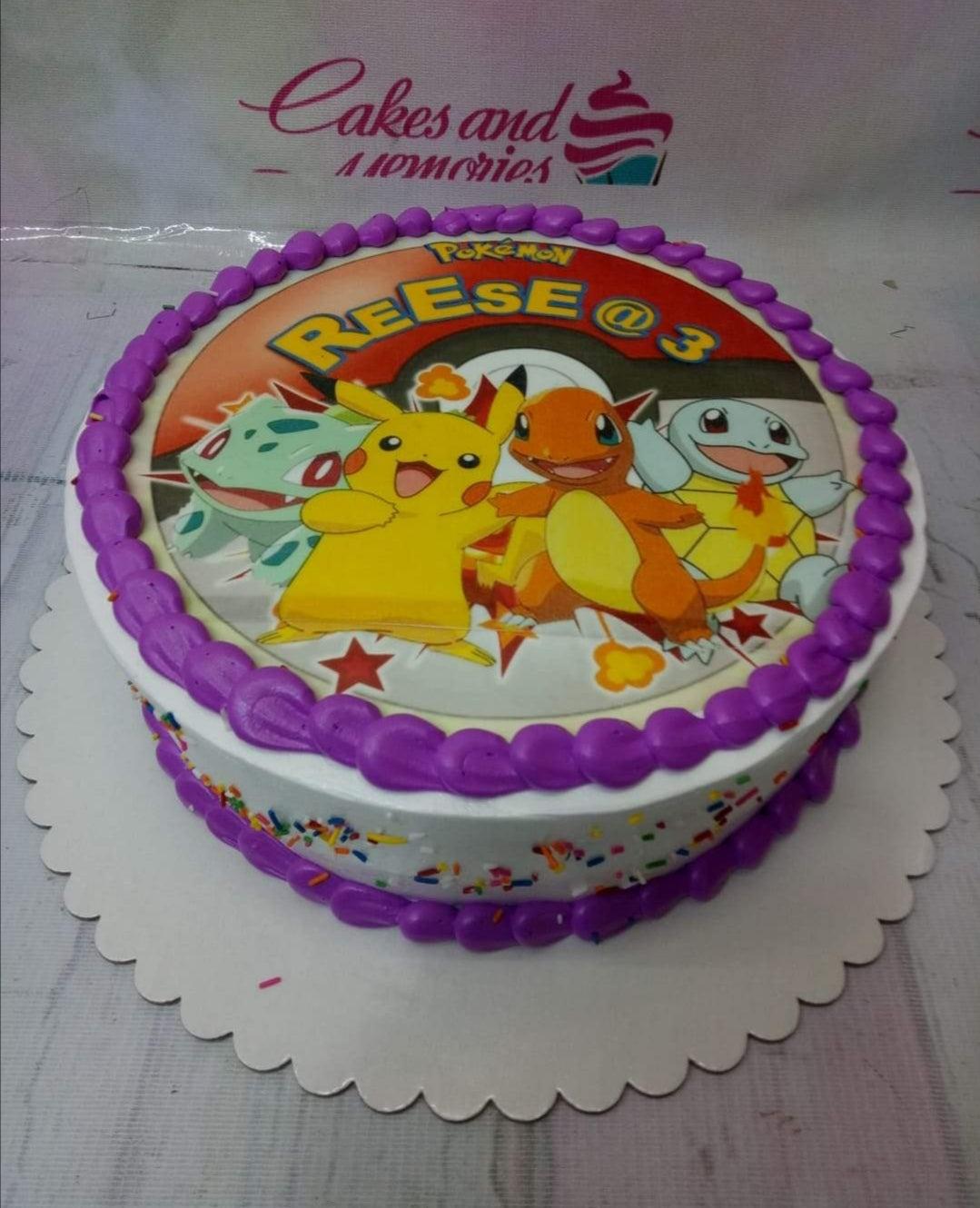 Round Pokemon birthday cake with edible print of Pikachu, Charmander, Squirtle, and Bulbasaur, featuring purple icing borders and sprinkles.