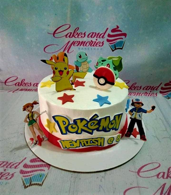 White Pokemon birthday cake with Pikachu, Bulbasaur, Squirtle, and Charmander printouts, red and blue stars, and a Pokeball topper.