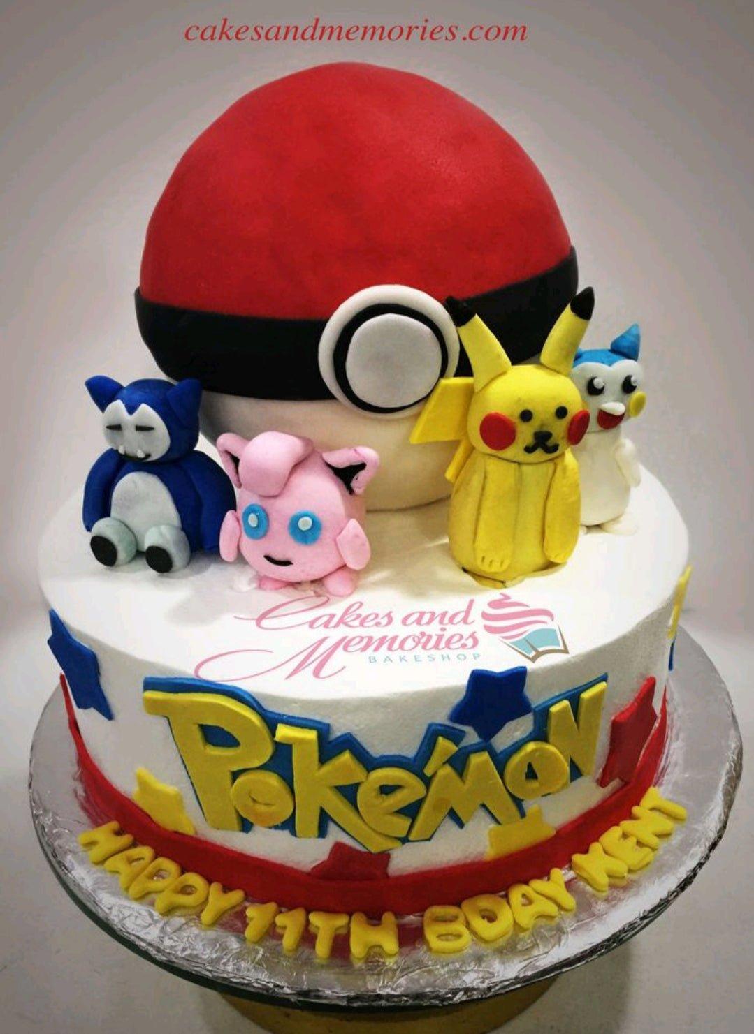 Pokemon themed birthday cake with a large 3D Pokeball topper and fondant figures of Snorlax, Jigglypuff, Pikachu, and Marill.