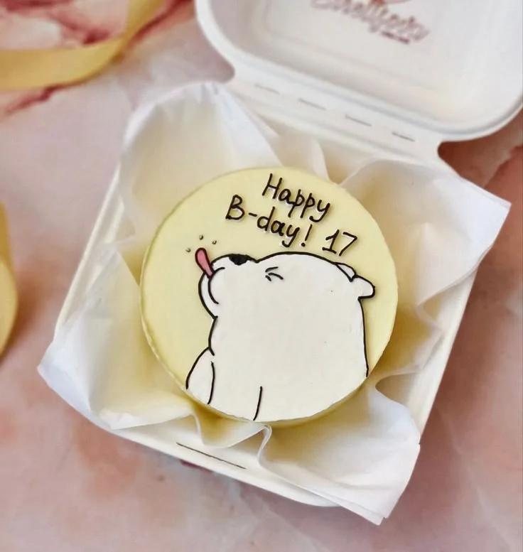 Bento cake with a hand-drawn white polar bear sticking its tongue out on a light yellow icing base with a birthday message.