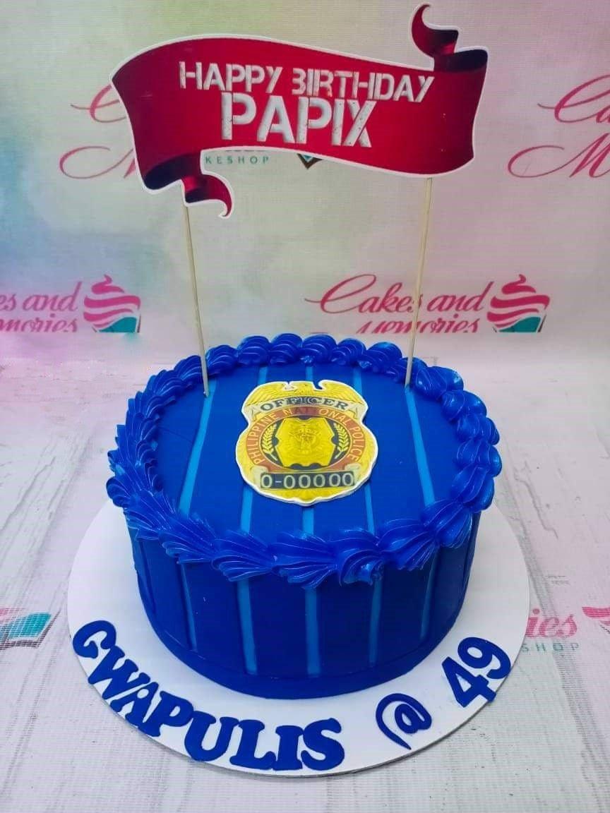 Blue police themed birthday cake with a Philippine National Police badge and a red banner topper for Papix.