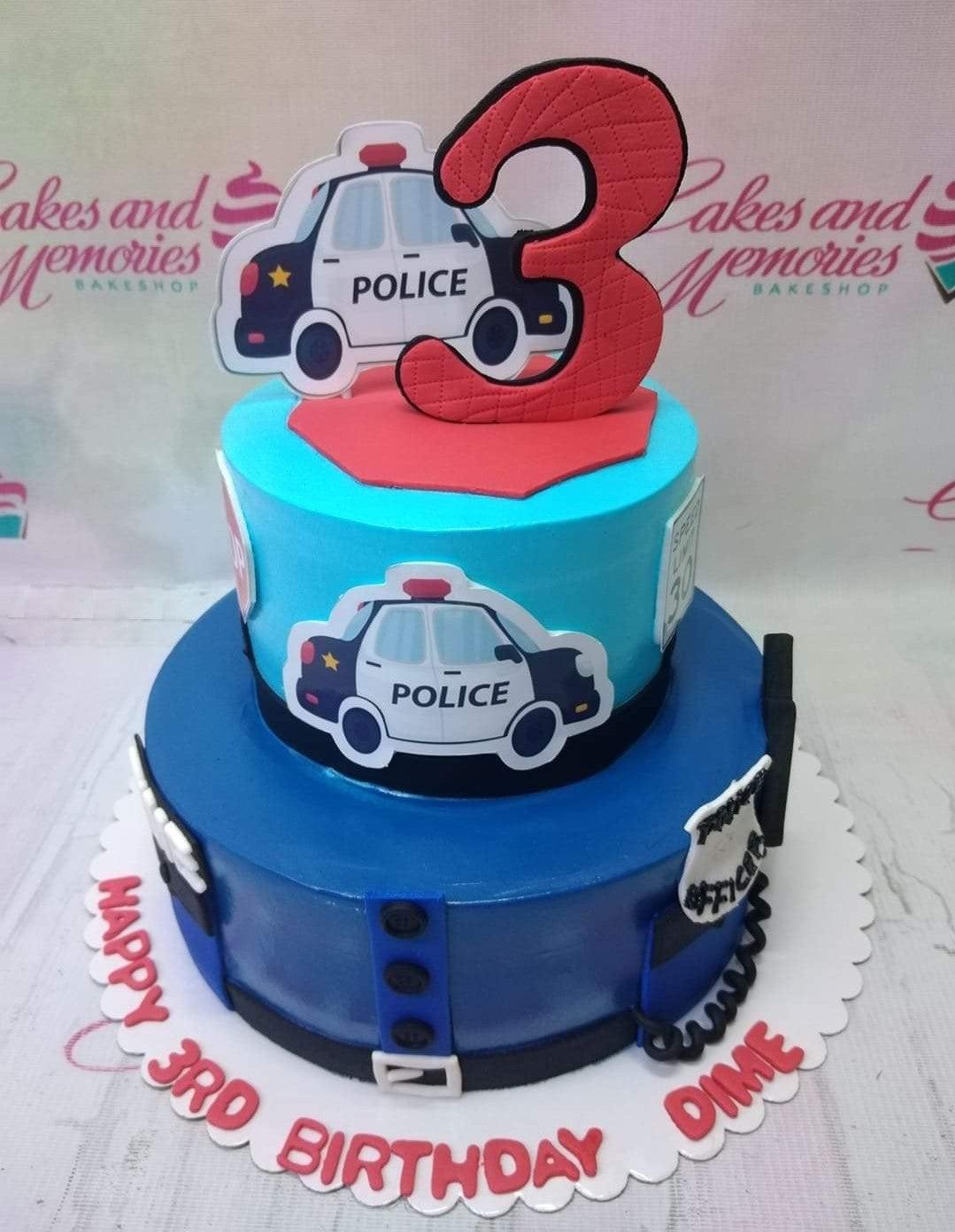 Two-tier police themed birthday cake in light and dark blue fondant with police car cutouts and a large red number three topper.
