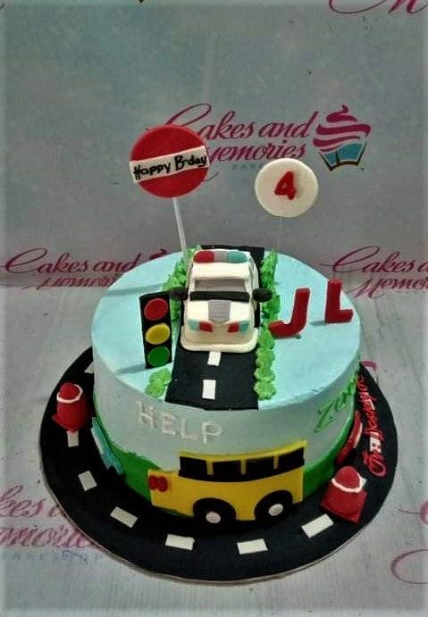 Police and transportation themed birthday cake with a 3D police car, traffic light, and road design on light blue icing.