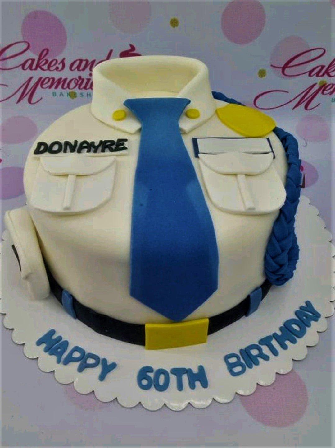 Police uniform cake with blue tie, name badge, and 60th birthday message on the base board.