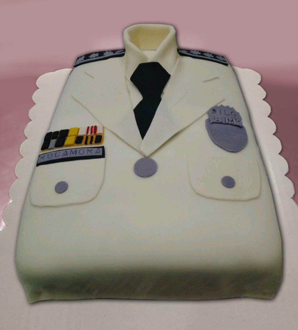 A white police uniform cake with a black tie, shoulder epaulettes, a name tag reading ROCAMORA, and a BJMP badge.