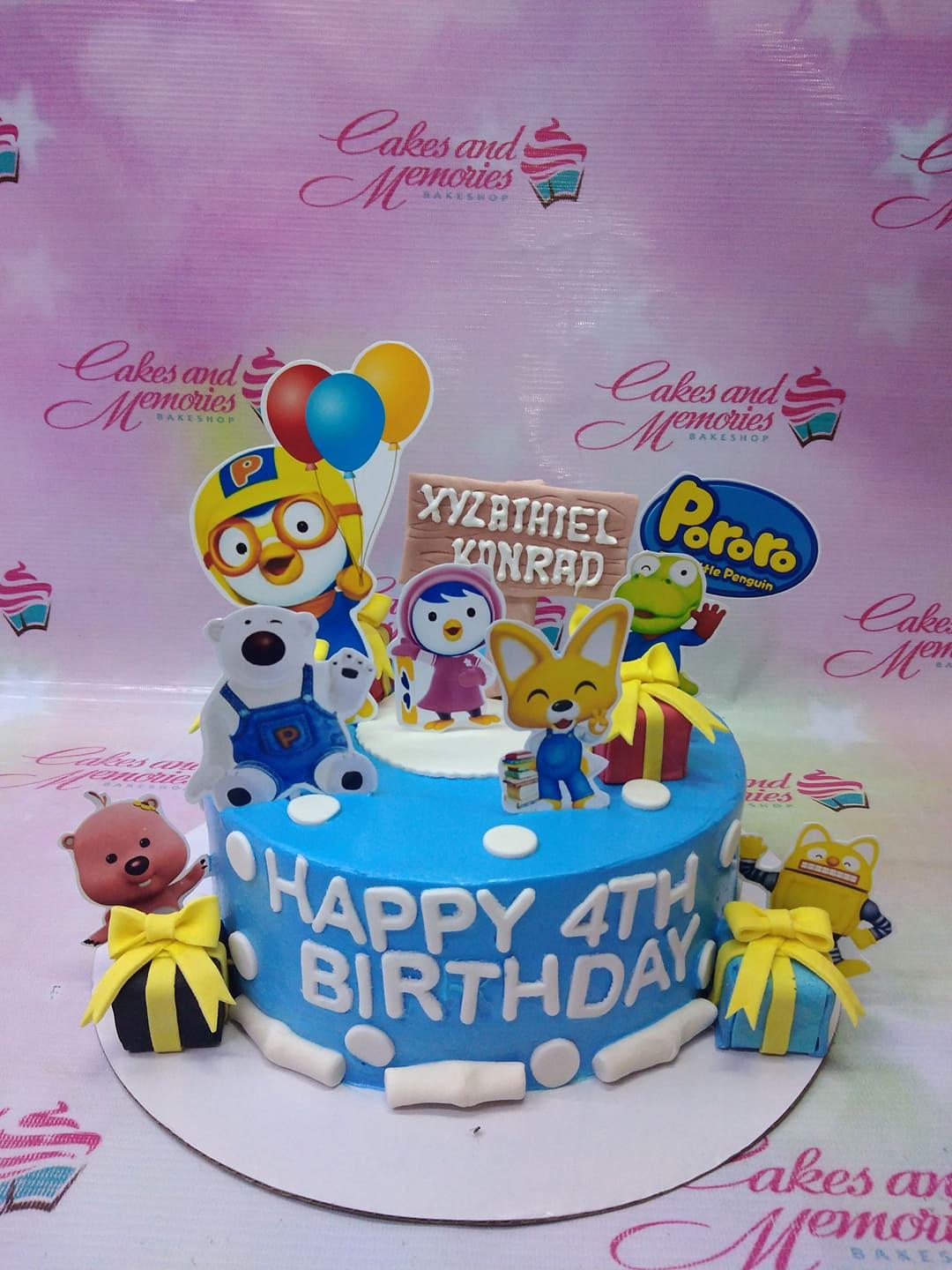 Blue Pororo the Little Penguin themed birthday cake with character printouts, fondant gift boxes, and white icing dots.