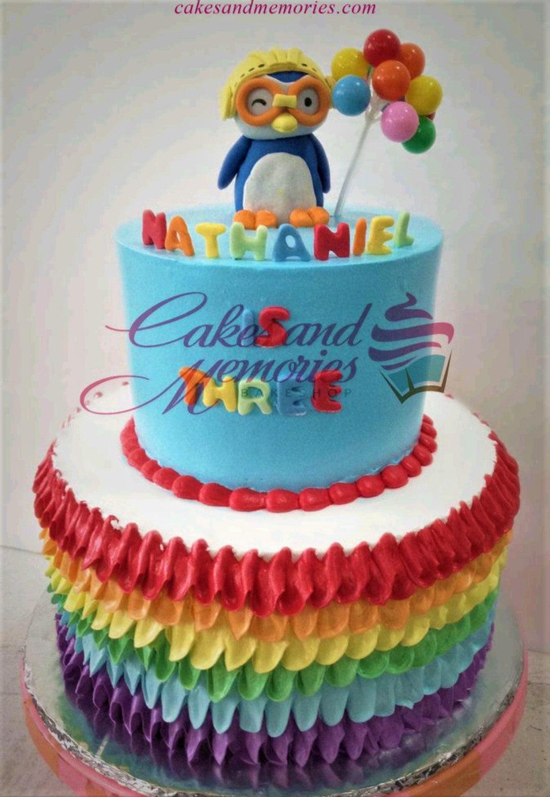 Two-tier Pororo the Little Penguin birthday cake with rainbow ruffles and a 3D Pororo figure holding balloons.