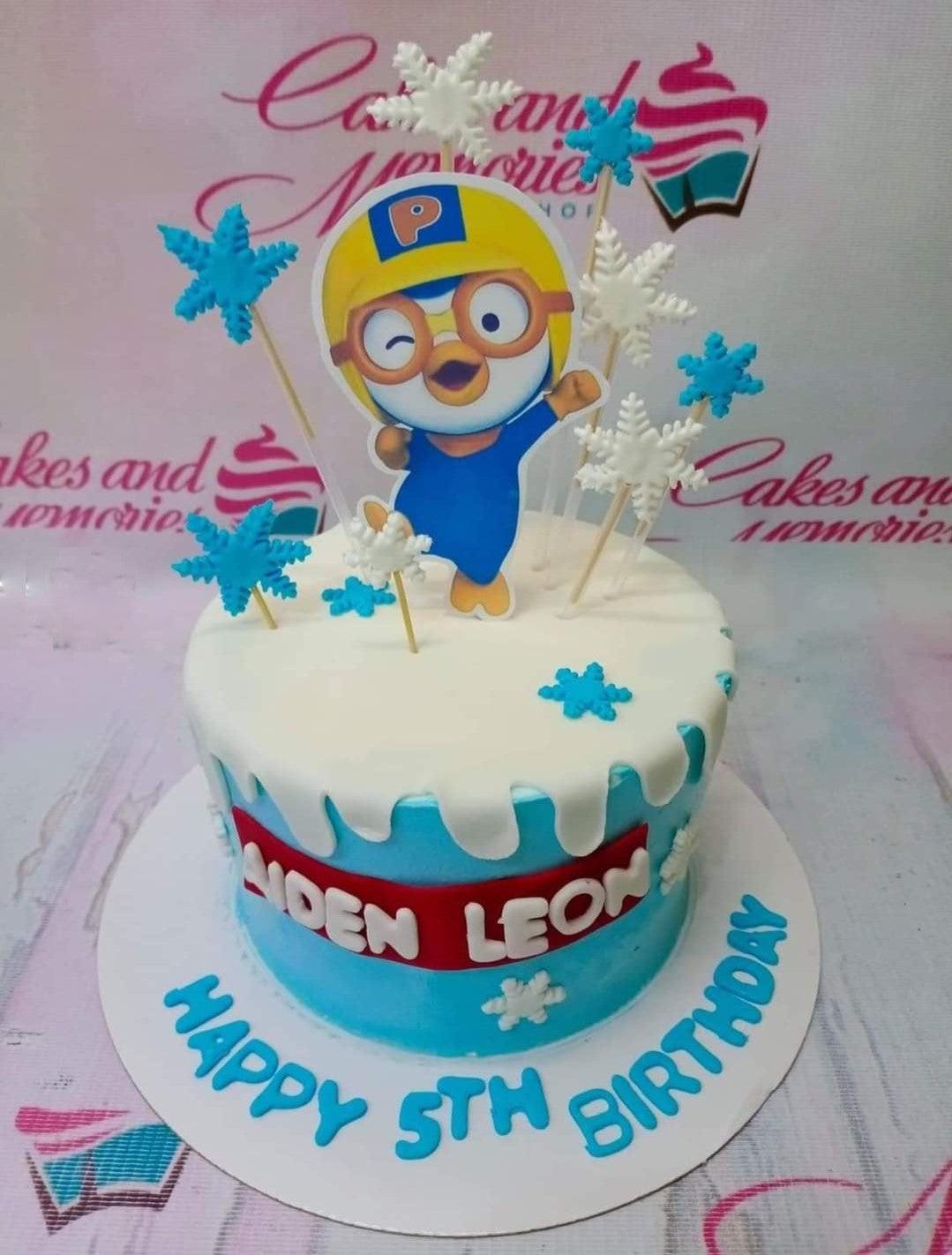 Light blue Pororo the Little Penguin birthday cake with white icing drip, snowflakes, and a red name banner.
