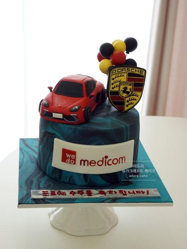 Teal and black marble fondant cake with a red 3D car topper, Porsche logo, and balloon cluster.