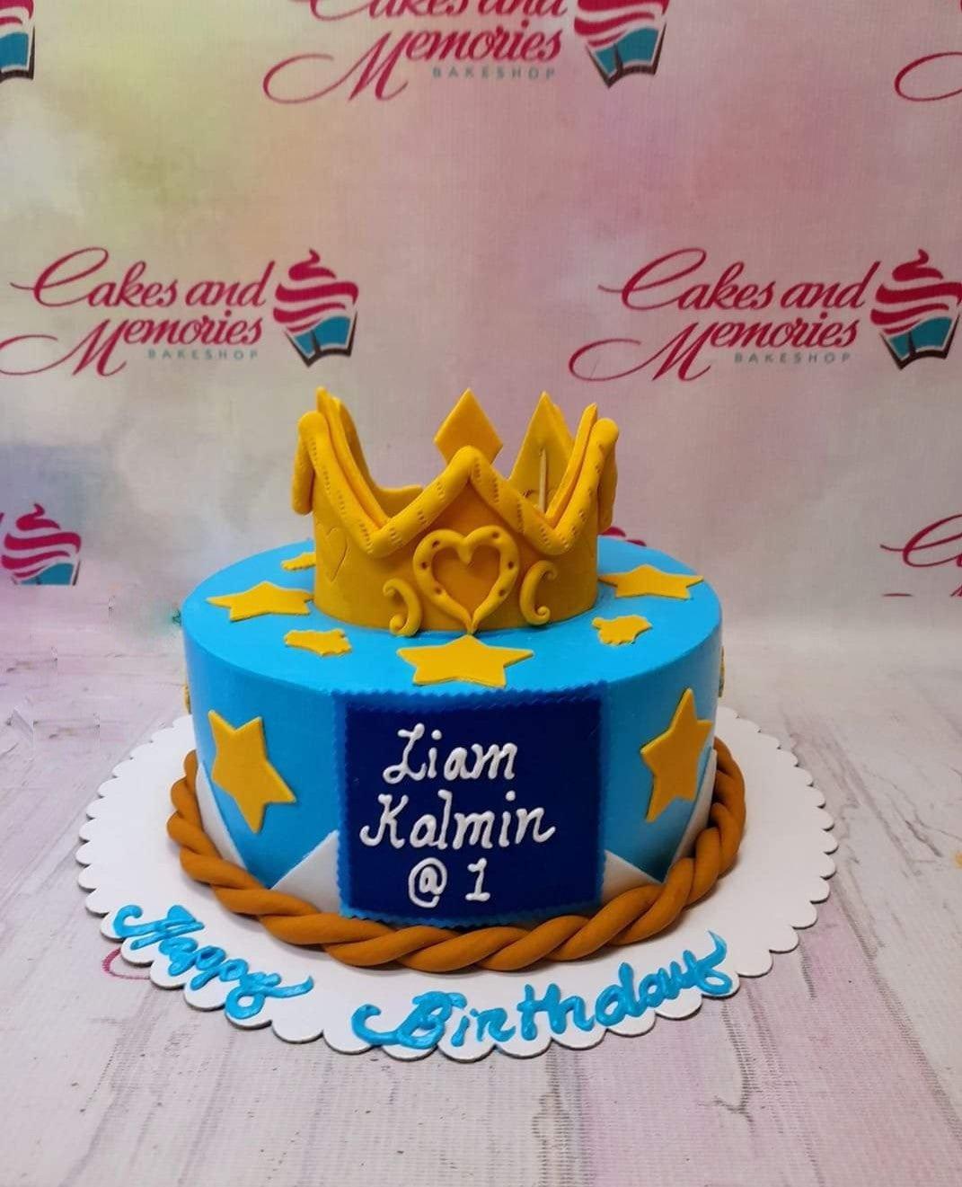 Blue 1-tier prince birthday cake with a large gold crown topper, yellow stars, and a blue name plaque.
