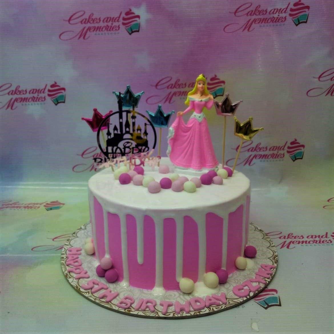 Pink and white princess themed cake with a 3D Aurora figurine, castle printout, and pink icing drips.