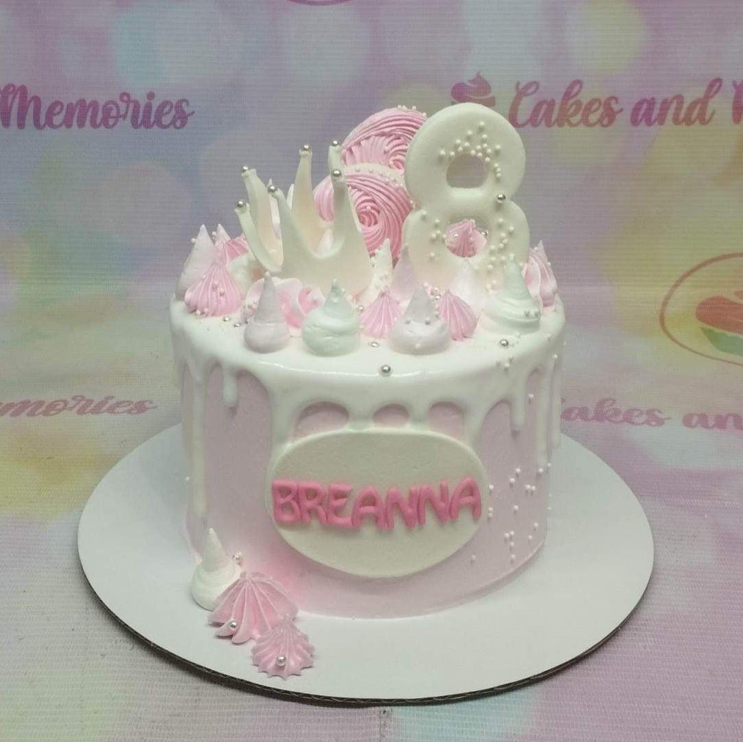 Pink 1-tier birthday cake with white drip, pink and white meringue kisses, a white number 8 topper, and a white crown.