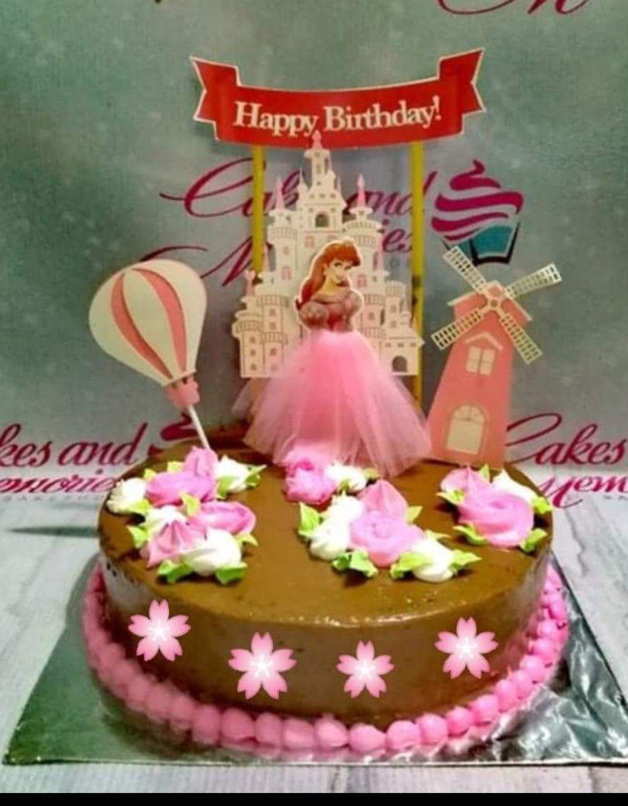 Princess themed chocolate cake with a pink tulle skirt topper, castle printout, and pink icing rosettes.