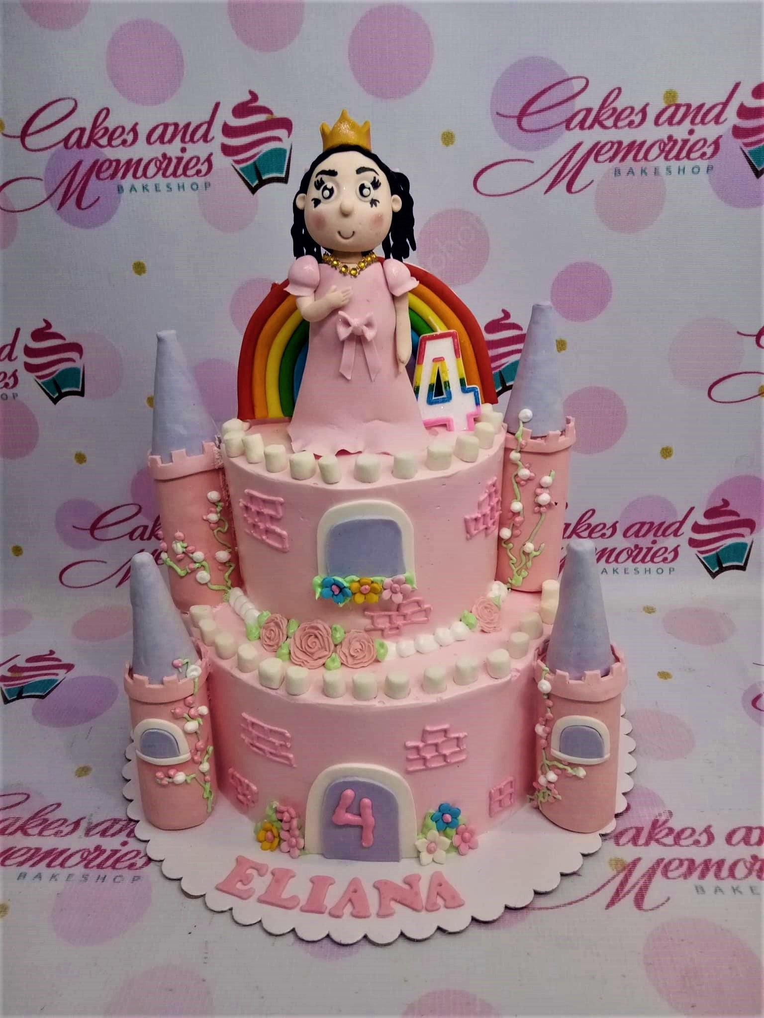 Pink 2-tier castle birthday cake with a fondant princess figure, rainbow, and castle towers for Eliana's 4th birthday.