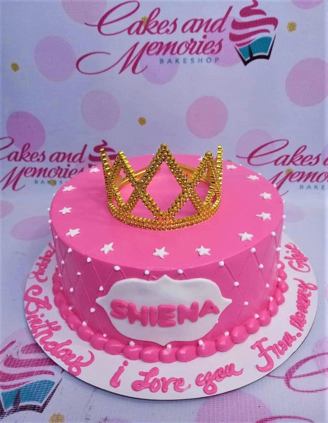 Pink princess birthday cake with a gold crown topper, white stars, and quilted icing pattern.