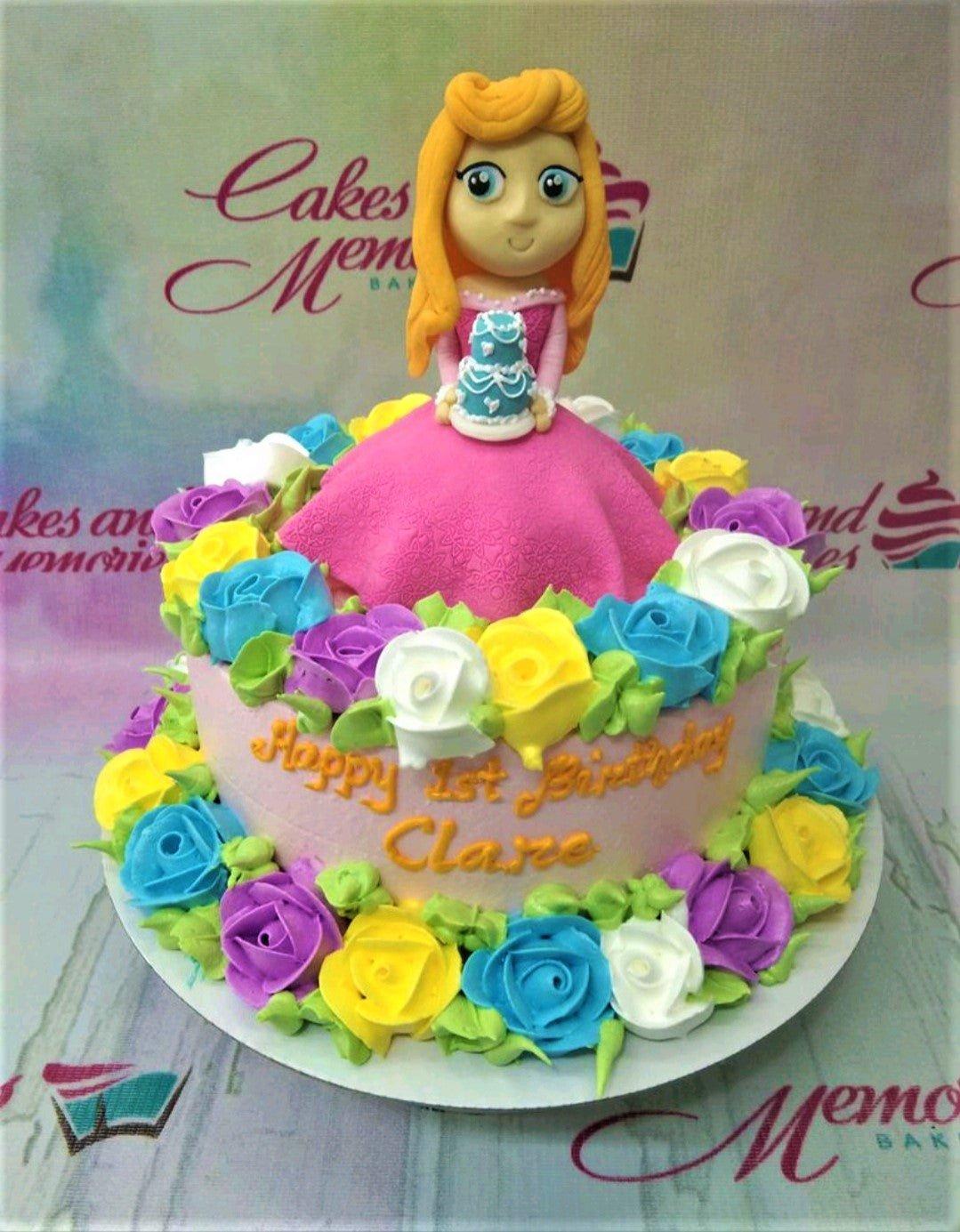 Pink princess doll cake with a large pink fondant skirt and colorful icing roses in blue, yellow, purple, and white.