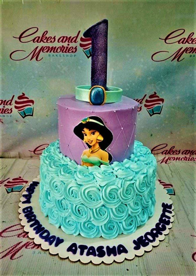 Two-tier Princess Jasmine themed cake with purple fondant top tier and light blue icing rosettes on the bottom tier.