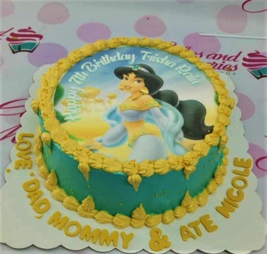 Teal Princess Jasmine birthday cake with yellow icing rosettes and a printed character topper.