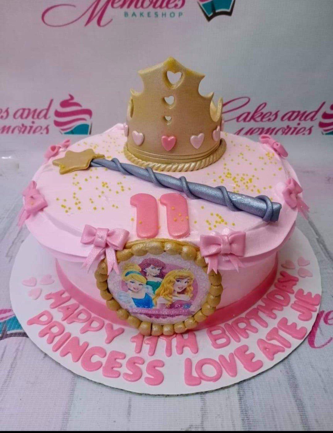 Pink princess birthday cake with a gold crown, magic wand, and Disney Princess edible printout on the side.