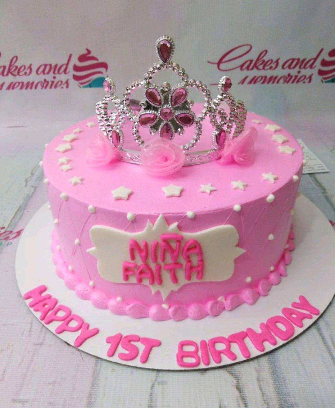 Pink princess birthday cake with a silver rhinestone tiara, white stars, and a custom name plaque.