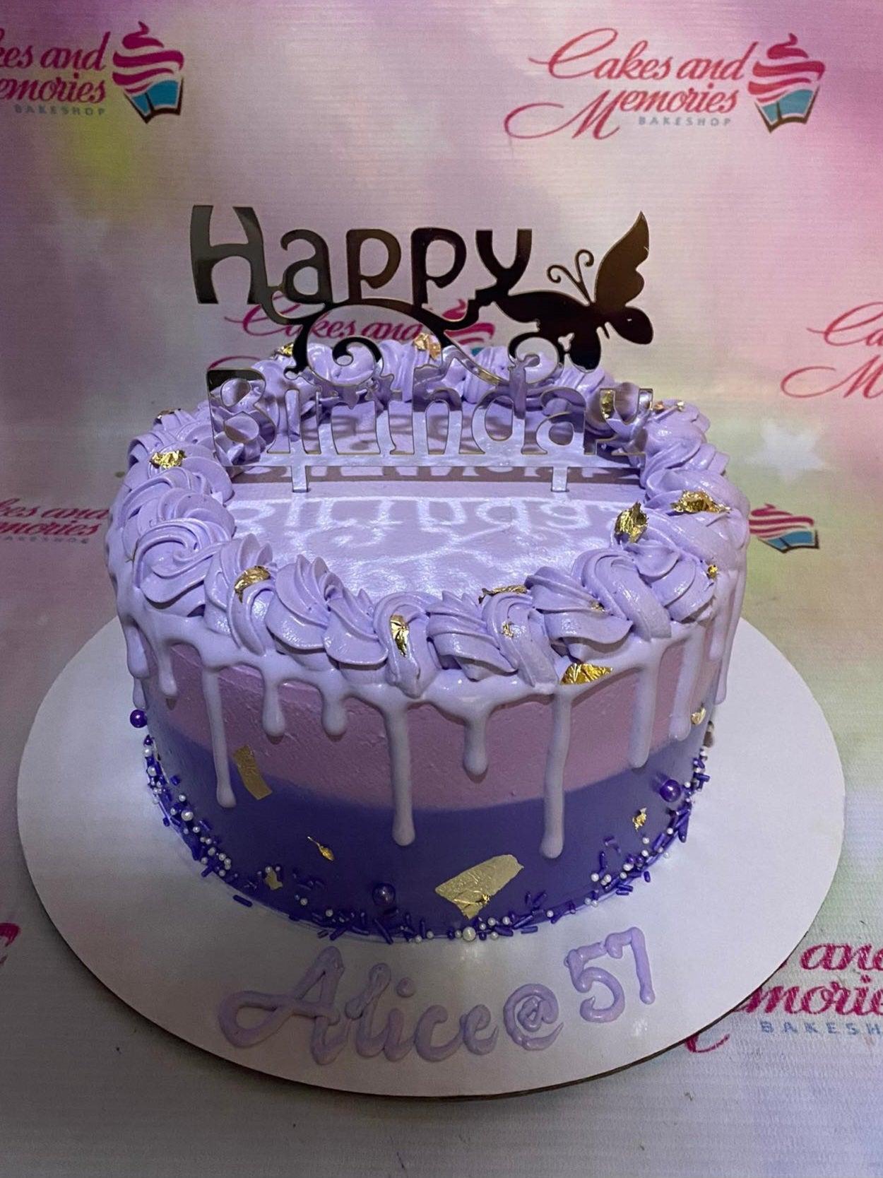 Purple ombre drip cake with gold leaf accents, purple sprinkles, and a Happy Birthday butterfly topper for Alice's 57th birthday.
