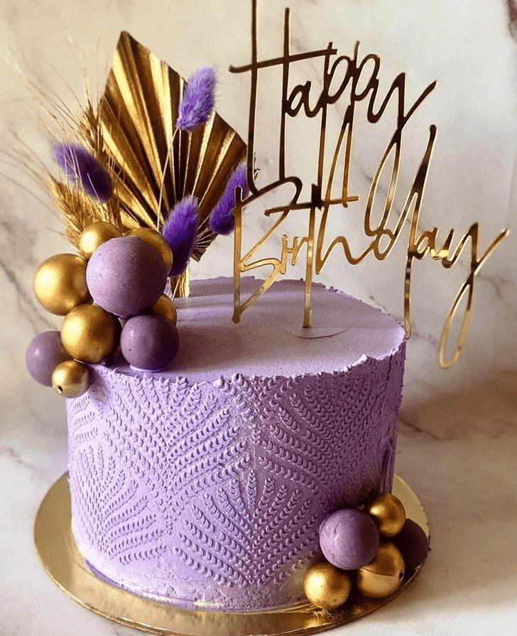 Purple textured birthday cake with gold and purple spheres, a gold palm leaf, and a gold Happy Birthday topper.