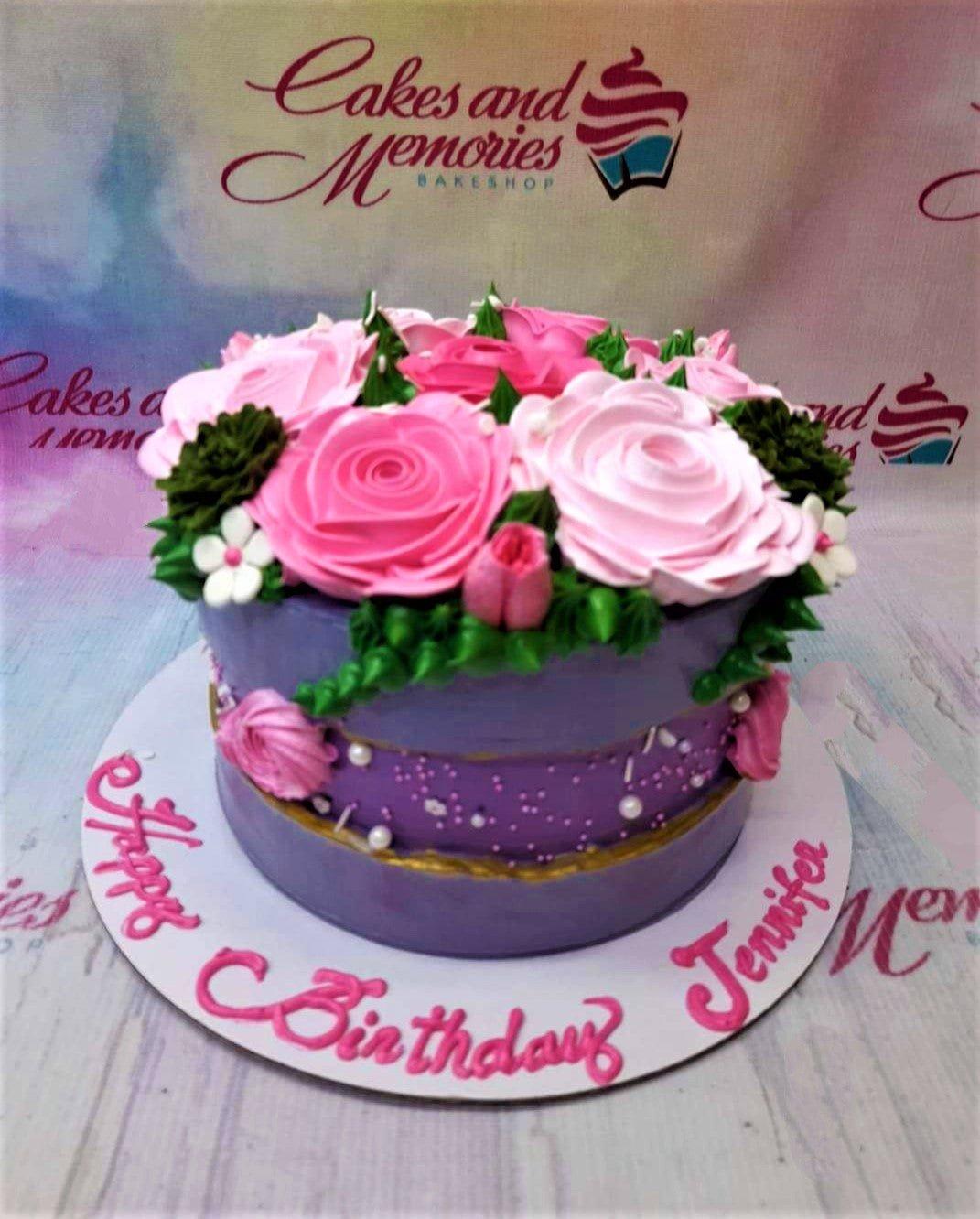 Purple birthday cake with pink and white icing roses on top and a personalized message on the base board.