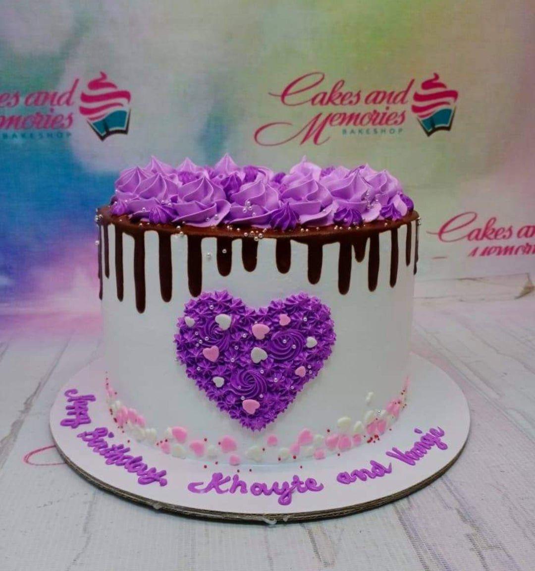 White 1-tier birthday cake with purple icing rosettes, chocolate drip, and a purple piped heart design.