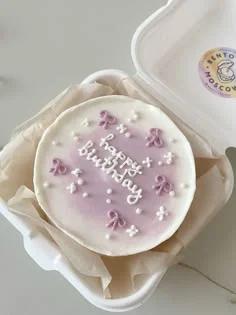 Purple and white bento cake with piped icing bows and white sprinkles for a birthday celebration.