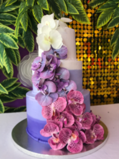 Elegant three-tier purple ombre cake decorated with a cascading trail of white and purple orchids.