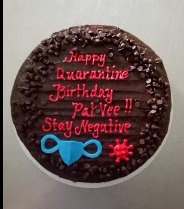 Chocolate cake with dark chocolate frosting, chocolate chips, and a pink message about a quarantine birthday with a blue mask and red virus icon.