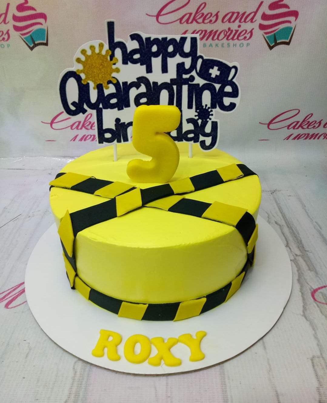 Yellow quarantine themed birthday cake with black and yellow hazard tape design and a large number 5 topper.