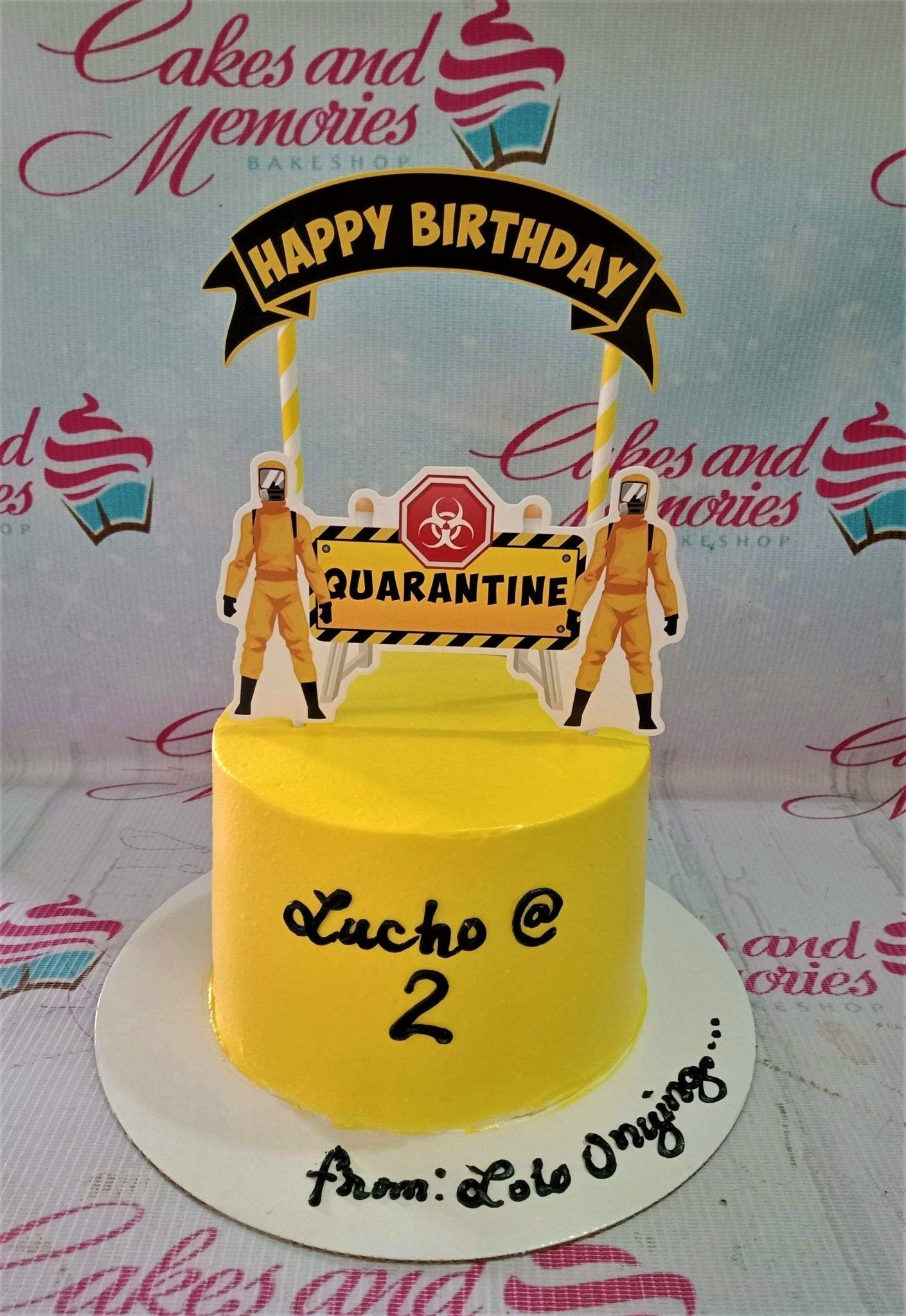 Yellow quarantine themed birthday cake with hazmat suit printouts and a biohazard warning sign topper.