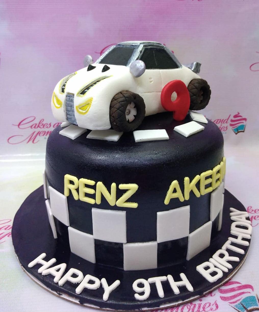 Black fondant racing car cake with a 3D white sports car topper, checkered flag pattern, and yellow name letters.