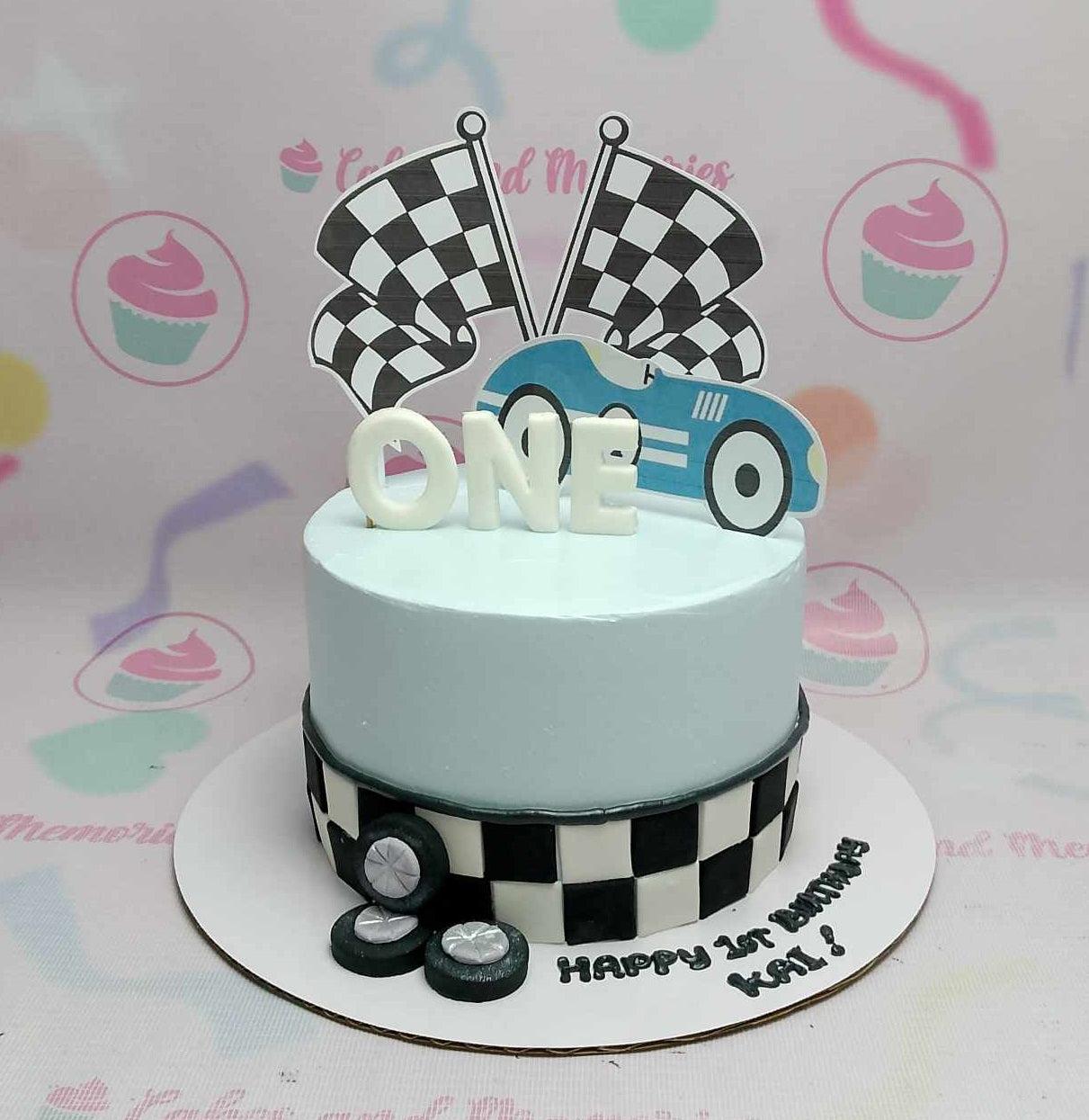 Light blue racing themed birthday cake with checkered flag printouts, a blue race car, and fondant tires.