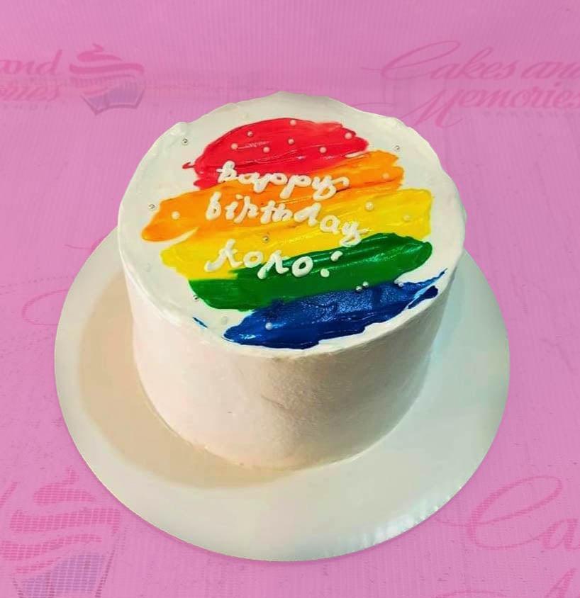 Bento cake with white icing and a vibrant rainbow palette knife design on top featuring a Happy Birthday message.