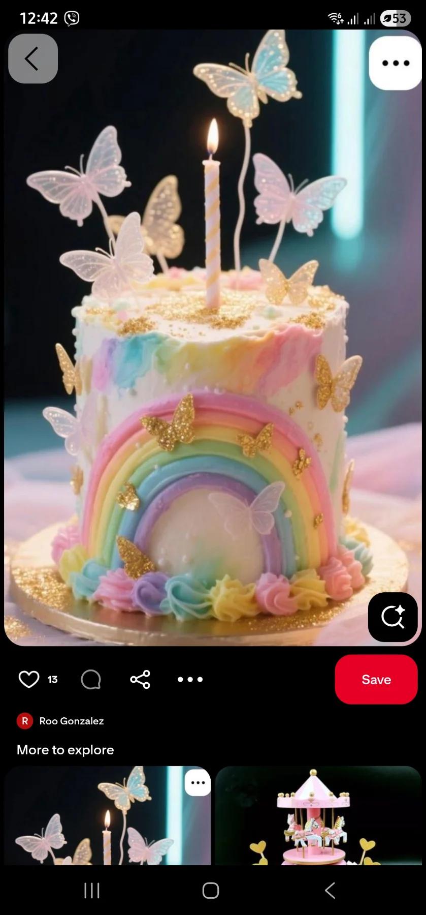 A tall white cake with a pastel rainbow icing design, gold glitter butterflies, and translucent butterfly toppers with a single candle.