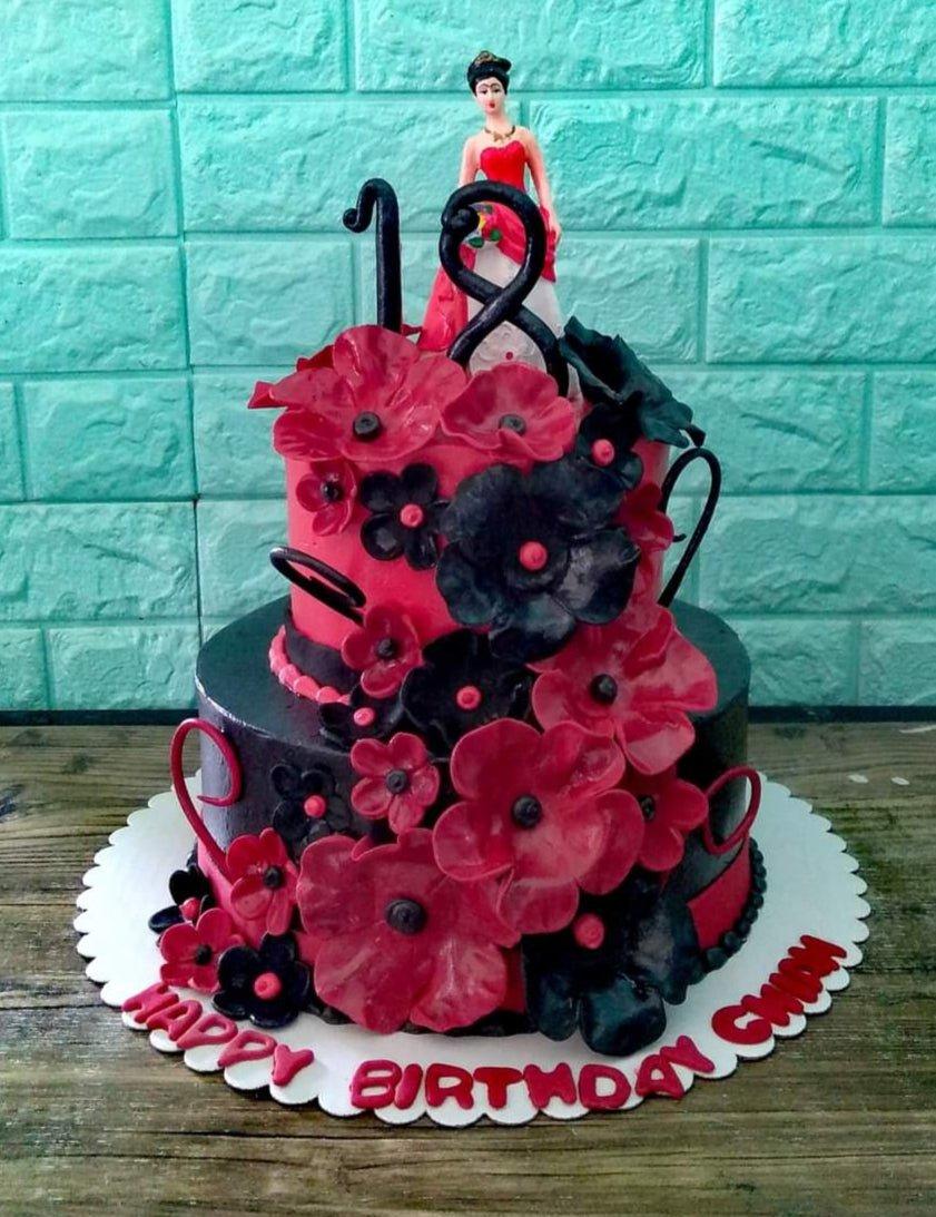 Two-tier red and black floral birthday cake with a lady figurine and number 18 topper.