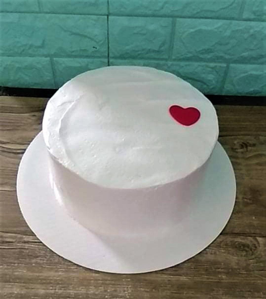 Minimalist white bento cake with a single small red heart decoration on top.