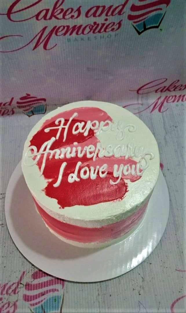 Minimalist white bento cake with red and pink palette knife icing strokes and white piped anniversary message.