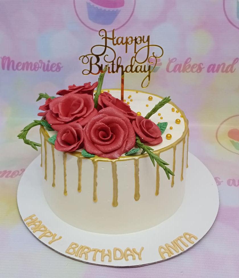 White 1-tier birthday cake with red gumpaste roses, gold drip, and a gold Happy Birthday topper.