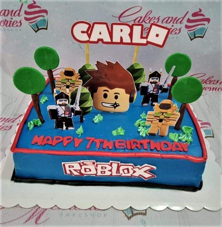 Blue Roblox themed rectangle birthday cake for Carlo's 7th birthday with character printouts and green icing trees.