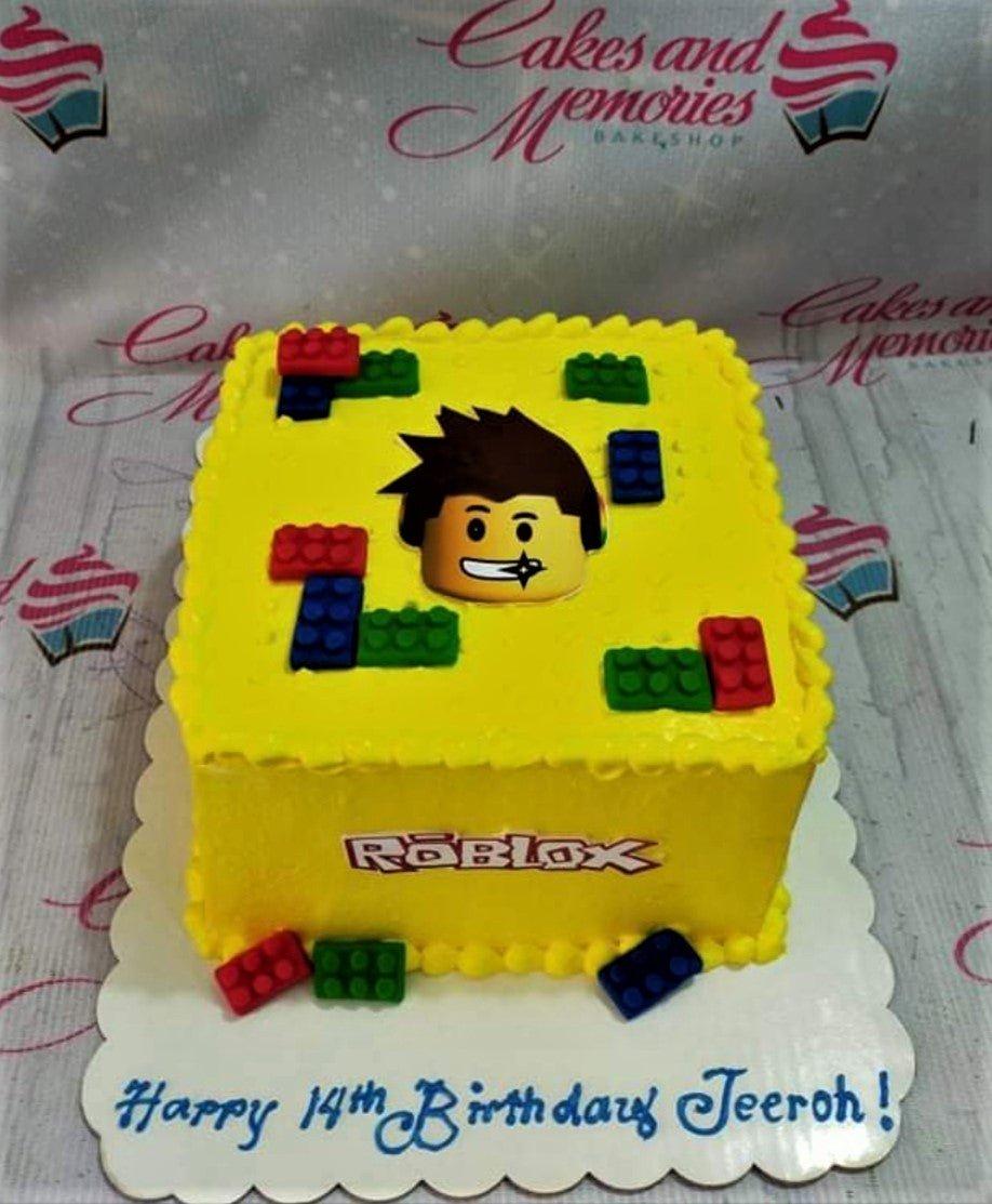 Yellow square Roblox birthday cake with edible Lego brick decorations and a Roblox character face topper.
