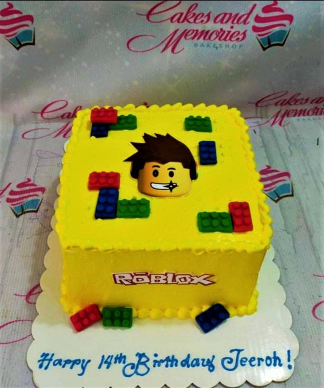 Yellow square Roblox birthday cake with edible lego brick decorations and a Roblox character printout.