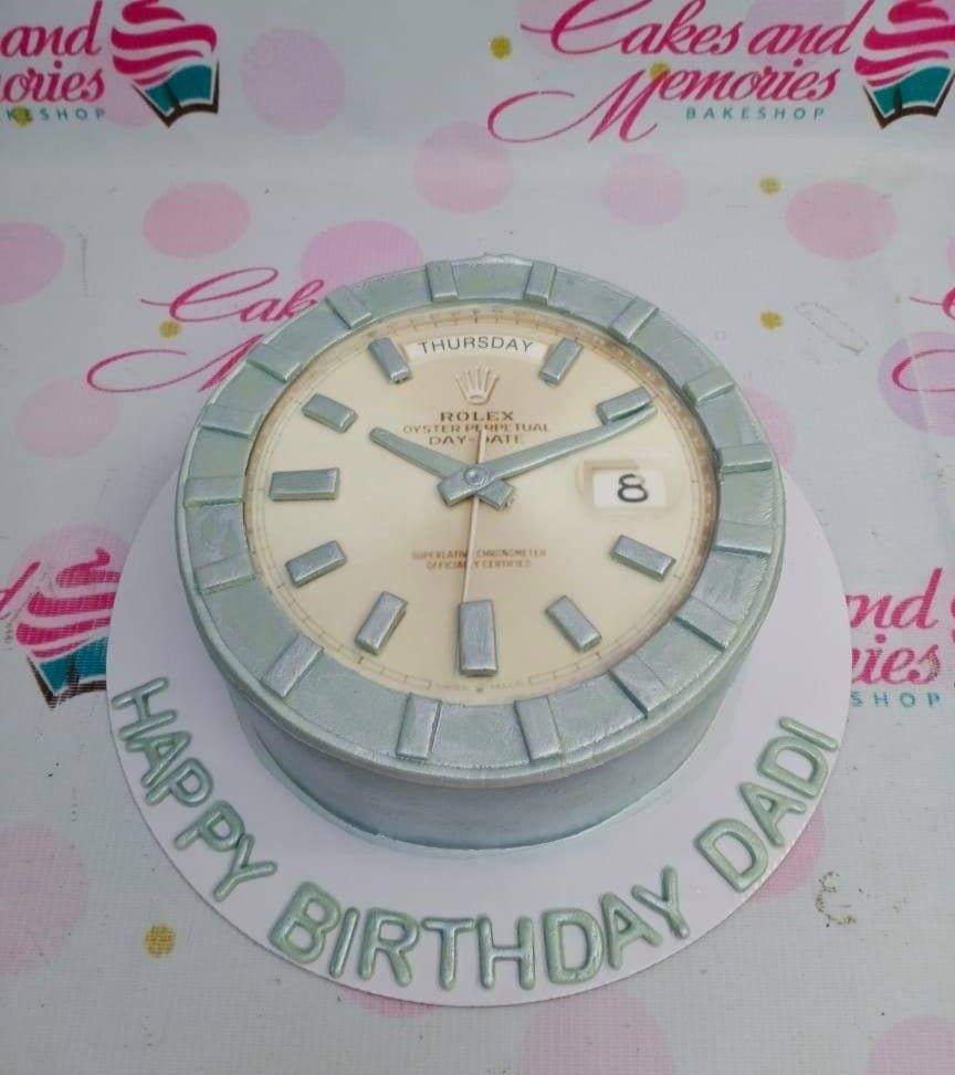 Silver Rolex watch themed cake with a detailed watch face and 'Happy Birthday Dadi' message on the base board.