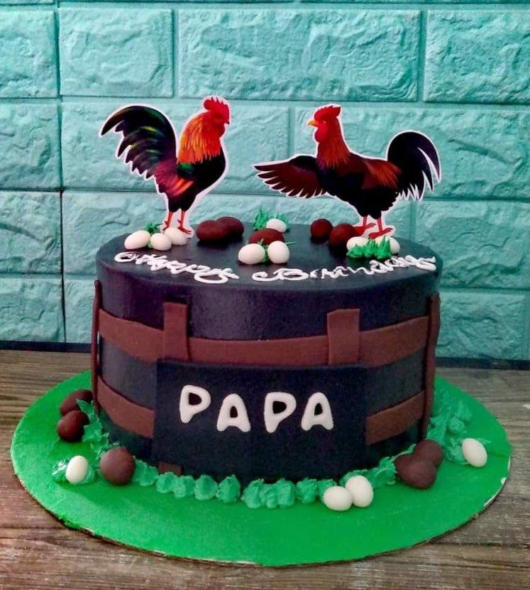 Black rooster themed birthday cake with brown fence panels, green icing grass, and white and brown edible eggs.