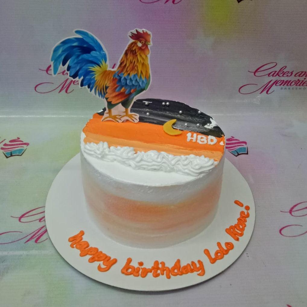 A single-tier birthday cake featuring a colorful rooster printout topper, sunset-themed icing, and a personalized message on the base board.